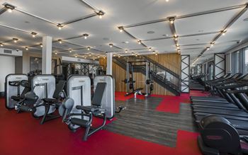 a gym with cardio equipment and a staircase
